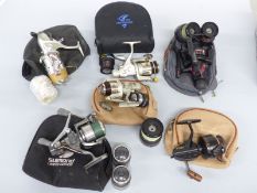 A collection of fixed spool fishing reels, some with multiple spare spools, most with cases,