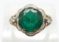 A yellow metal ring set with a synthetic emerald and two diamonds,