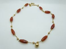 A gold necklace of faceted barrel shaped carnelian agate beads with alternating gold spherical