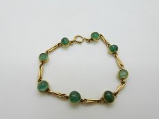 A yellow metal bracelet set with emerald cabochons, 19.