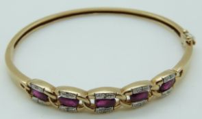 A 9ct gold bangle set with five oval cut rubies and diamonds, 12.