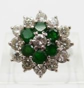 An 18ct white gold ring set with diamonds and emeralds in a cluster,