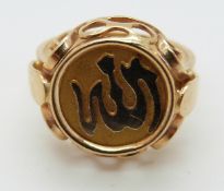 A yellow metal ring set with a circular panel depicting Arabic script, size O, 5.