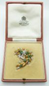 An 18ct gold bi-coloured brooch with textured leaves and set with emeralds and diamonds in a fitted