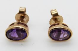 A pair of 9ct gold earrings set with an oval amethyst to each