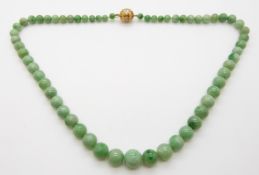 A jade necklace made up of spherical graduated beads with a filigree clasp