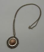 A hallmarked silver swimming fob with a yellow metal centre on a silver chain