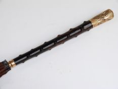 A late 19thC/20thC parasol with yellow metal and faux bamboo handle and hardwood stick,
