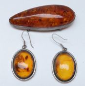 A large silver brooch set with a section of pressed amber and a pair of similar earrings