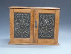Oak smoker's cabinet with embossed Art Nouveau / Arts & Crafts panels to front,