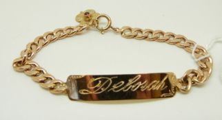 A yellow metal identity bracelet with gold flower charm set with a ruby,