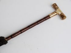 A late 19thC/20thC parasol with 18ct gold plated and mother-of-pearl handle on a bamboo stick,