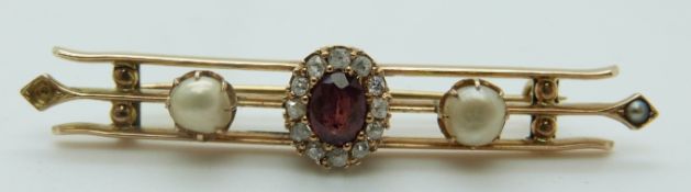 A Victorian brooch set with an oval cut garnet surrounded by diamonds and two further pearls (6.