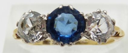 An 18ct gold ring set with two round cut sapphires and a blue paste central stone,