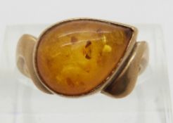 A 9ct gold ring set with a amber pressed cabochon,
