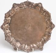 George V hallmarked silver salver with shaped edge, raised on three ball and claw feet,