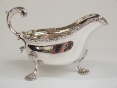 Edward VII hallmarked silver sauce boat with gadrooned edge and raised on shell-shaped feet,