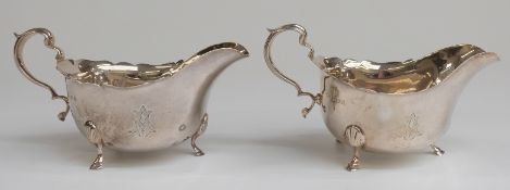 A pair of George V hallmarked silver sauce boats raised on three feet,