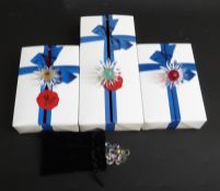 Three Swarovski Crystal cut glass coloured daisy ring holders, each 5cm in diameter,