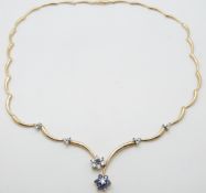 A 14ct gold necklace set with diamonds and sapphires in two floral clusters and 12 further diamonds