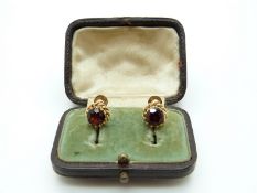 A pair of 15ct gold earrings set with a garnet to each