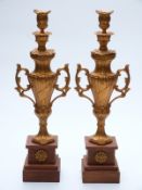 Pair of gilt urns on wooden stepped bases,