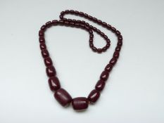 A cherry amber necklace made up of barrel shaped beads,