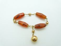 A gold bracelet of faceted barrel shaped carnelian agate beads with alternating gold spherical