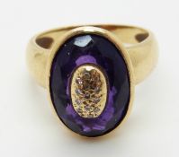 An 18ct gold ring set with a faceted oval amethyst with a central diamond set section,
