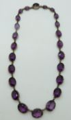 WITHDRAWN A Victorian white metal Riviere necklace of graduated oval amethysts,