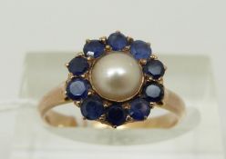 A yellow metal ring set with a pearl to the centre surrounded by sapphires,