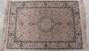 Perisan style rug or prayer mat with blue decoration and fringed ends on pale pink ground,