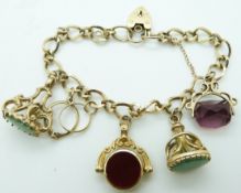 A 9ct gold charm bracelet with two 9ct gold fobs, two 9ct gold swivel fob charms and a ring charm,
