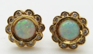 A pair of 18ct gold earrings set with an opal cabochon surrounded by diamonds