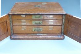 Oak cased 12 place setting canteen of cutlery with three drawers behind cupboard doors
