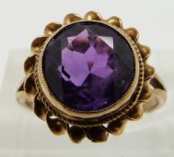 A 9ct gold ring set with a round cut amethyst with a twist border, size J