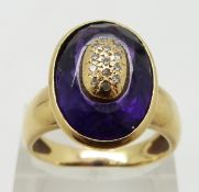 An 18ct gold ring set with a faceted amethyst and diamonds in an oval gold section to the centre,