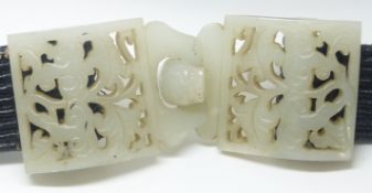 A 19th Century Chinese pierced and carved jade belt buckle in two parts, on later belt, 4.5 x 11 cm.