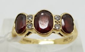 An 18ct gold ring set with three garnets and diamonds, size L