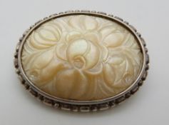 A silver brooch set with a carved mother of pearl plaque depicting flowers, 4.5 x 3.5cm