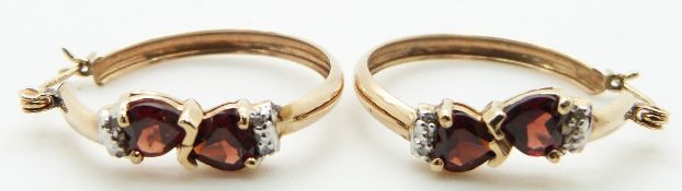 A pair of 10k gold earrings set with heart shaped garnets and diamonds