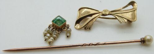 A 9ct gold bow brooch, an emerald and seed pearl charm and a stick pin set with a pearl