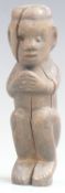 An 18thC / 19thC African carved wood tribal figure in seated position with clasped hands, 15cm