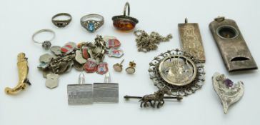 A collection of silver jewellery including a charm bracelet, pressed amber ring, silver whistle,