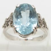 An 18ct white gold ring set with an oval mixed cut aquamarine and diamonds to the shoulders, size