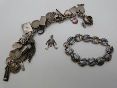 A silver/white metal charm bracelet with various charms including coins and enamel and a white metal
