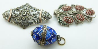A silver egg pendant set with enamel and two silver brooches