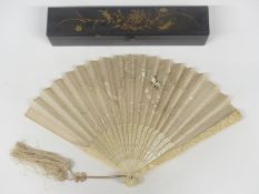 A 19th/20thC Chinese carved bone fan decorated with dragons, in lacquer box, length 22cm