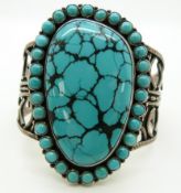 A silver bangle set with a large turquoise plaque