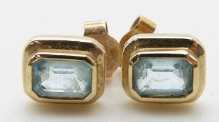 A pair of 9ct gold earrings set with an emerald cut blue topaz